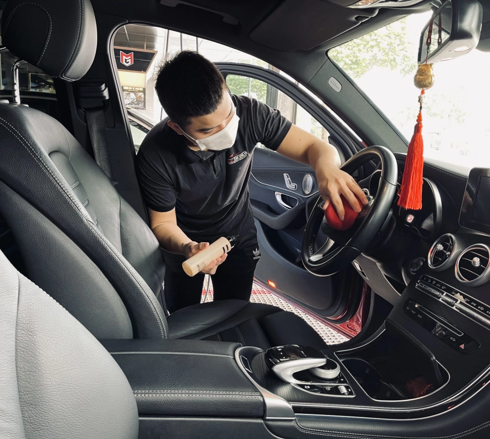 Một người thợ đang tỉ mỉ may bọc vô lăng da thật lên vô lăng xe hơi