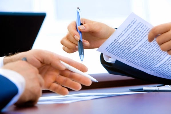 Một người đang kiểm tra giấy tờ trên bàn, với hợp đồng mua bán trả góp