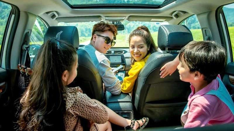 Một gia đình hạnh phúc đứng bên chiếc xe mới, tượng trưng cho quyết định tài chính thông minh