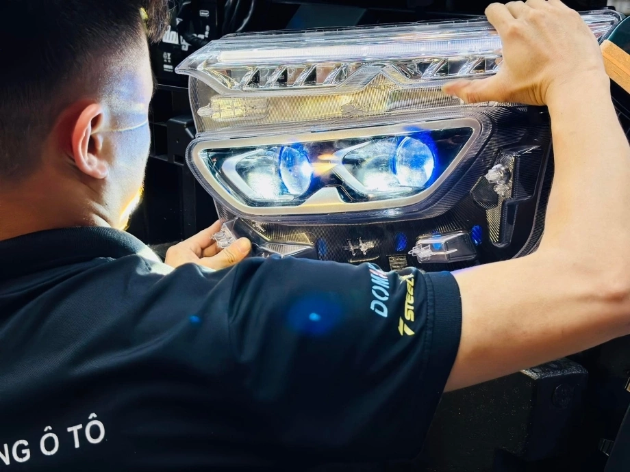 Một người đang kiểm tra đèn pha xe trong bóng tối