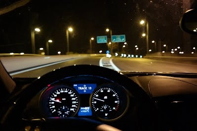 Bảng điều khiển xe hơi sáng lên trong đêm, hiển thị tốc độ và đèn pha