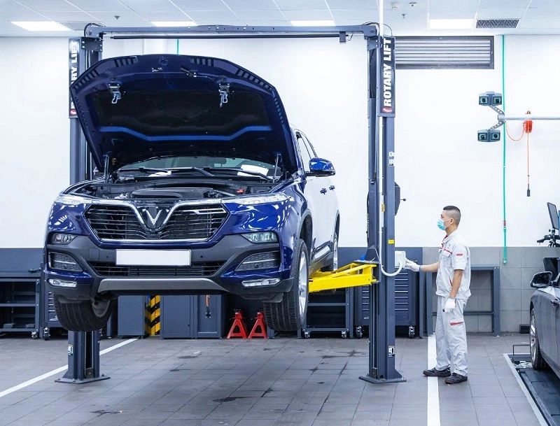 Một người đang kiểm tra pin xe điện tại trạm sạc, với các công cụ bảo dưỡng hiện đại xung quanh