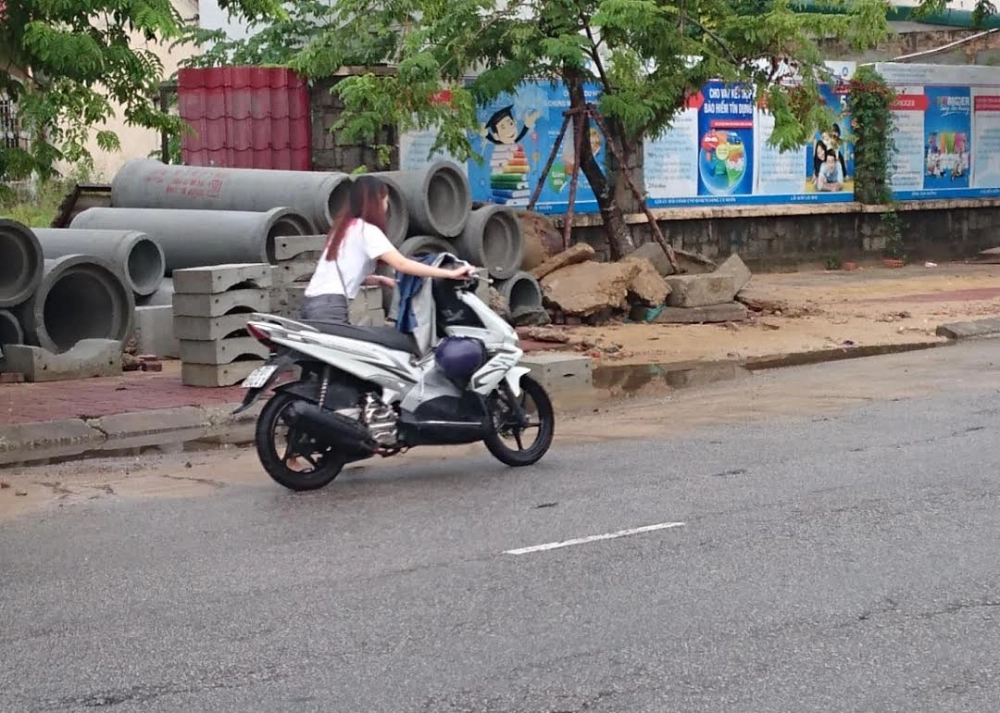 Một bạn trẻ đang dắt chiếc xe máy hỏng, với biểu cảm lo lắng