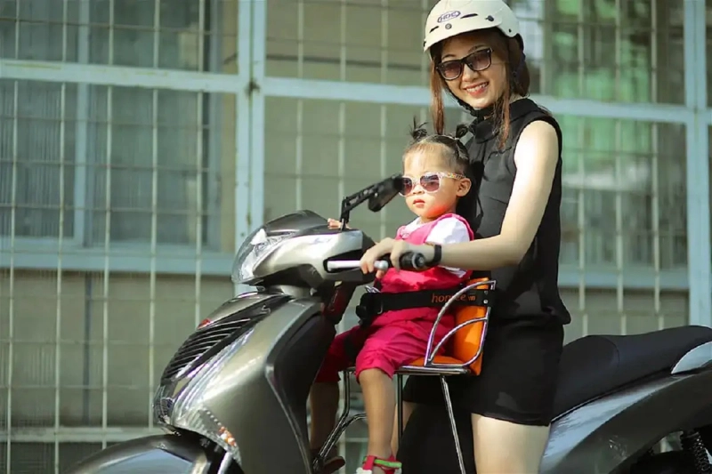 Một bạn trẻ vui vẻ ngồi trên chiếc xe máy vừa sửa xong, với nụ cười tự tin
