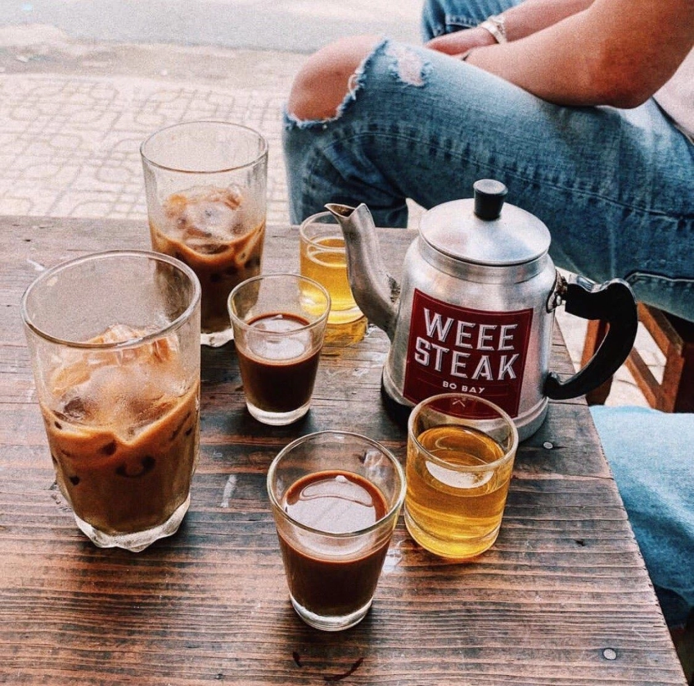 Một tài xế đang nghỉ ngơi bên lề đường, ngồi trên ghế với ly cà phê