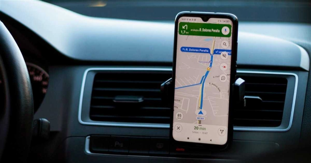 Tài xế đang nhập địa chỉ vào Google Maps trên điện thoại gắn ở bảng điều khiển
