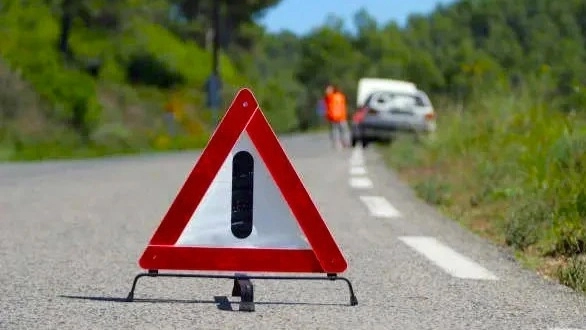 Một chiếc xe được đặt trên bề mặt phẳng với biển cảnh báo tam giác phía sau