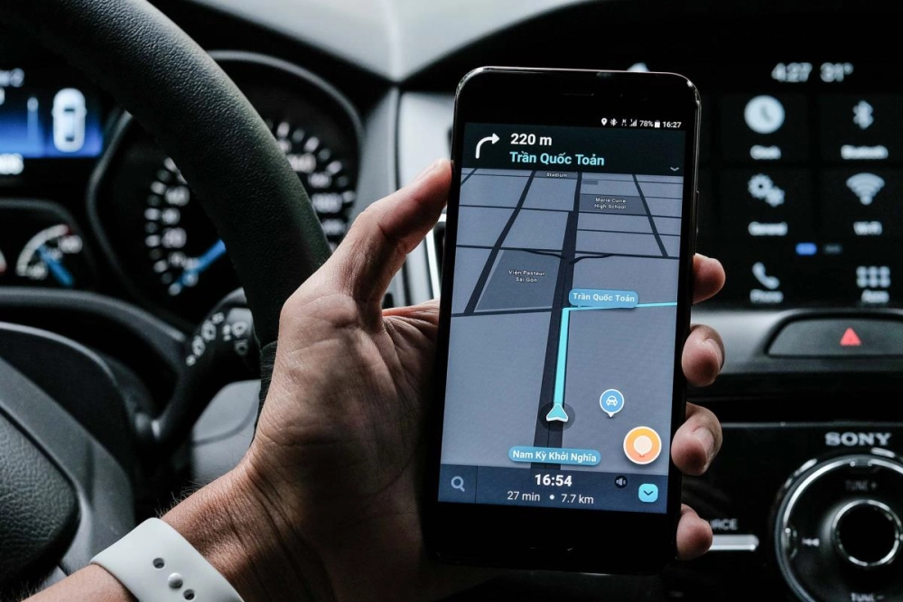  Một tài xế đang sử dụng smartphone với giao diện ứng dụng điều hướng trên xe hơi
