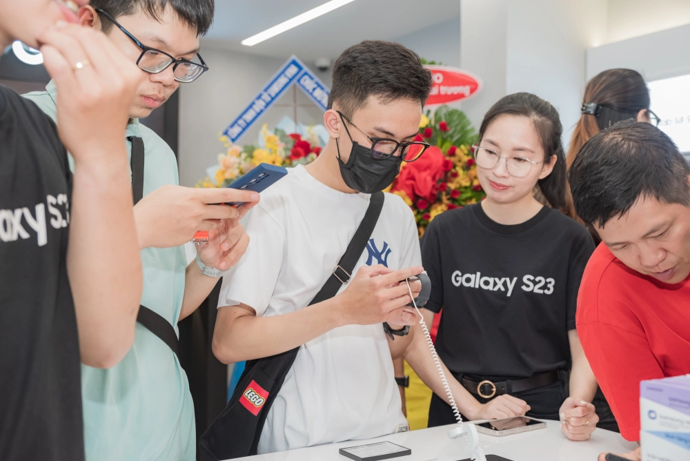 Khách hàng đang trải nghiệm các mẫu điện thoại mới, thể hiện sự quan tâm của họ đến xu hướng và thị phần điện thoại tại Việt Nam.