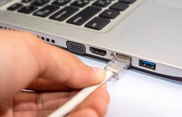 Sợi cáp Ethernet đang được cắm vào cổng LAN của một chiếc laptop