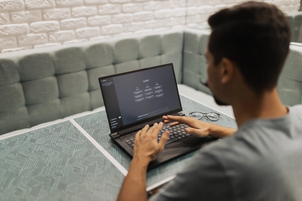 Một người trẻ đang nhập câu lệnh vào ChatGPT trên laptop