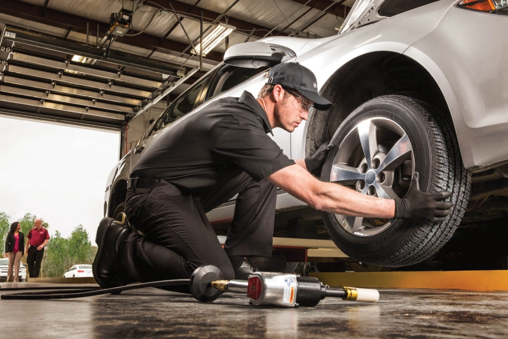 Một kỹ thuật viên đang kiểm tra lốp xe trong xưởng bảo dưỡng, với các dụng cụ chuyên dụng xung quanh