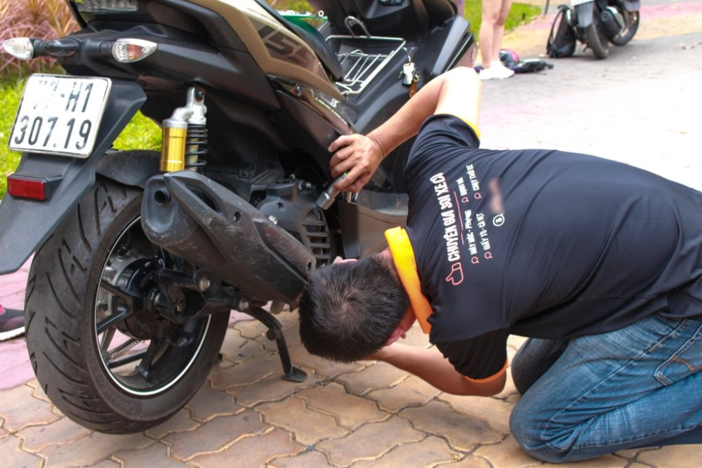 Một chiếc xe máy cũ bị hỏng động cơ, với thợ đang sửa chữa