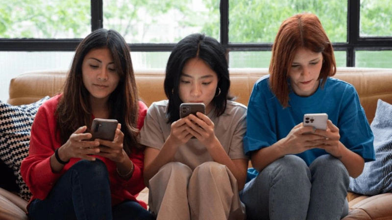 Một nhóm bạn trẻ đang thảo luận về các mẫu xe máy cũ trên smartphone