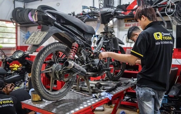 Một người đang kiểm tra động cơ xe máy cũ tại cửa hàng