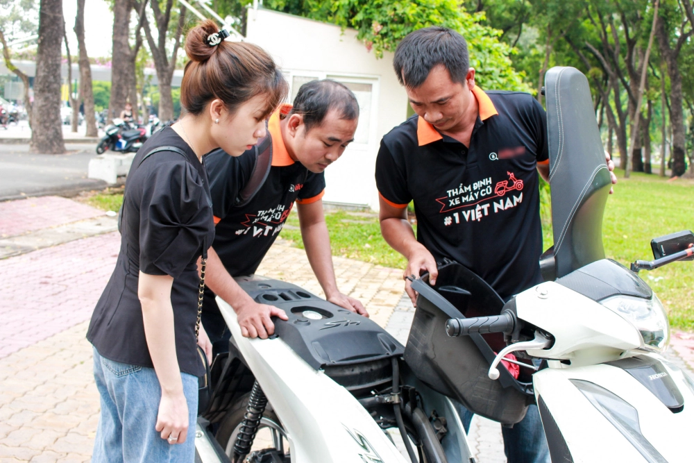 Một người trẻ đang bối rối khi kiểm tra xe máy cũ do thiếu kinh nghiệm